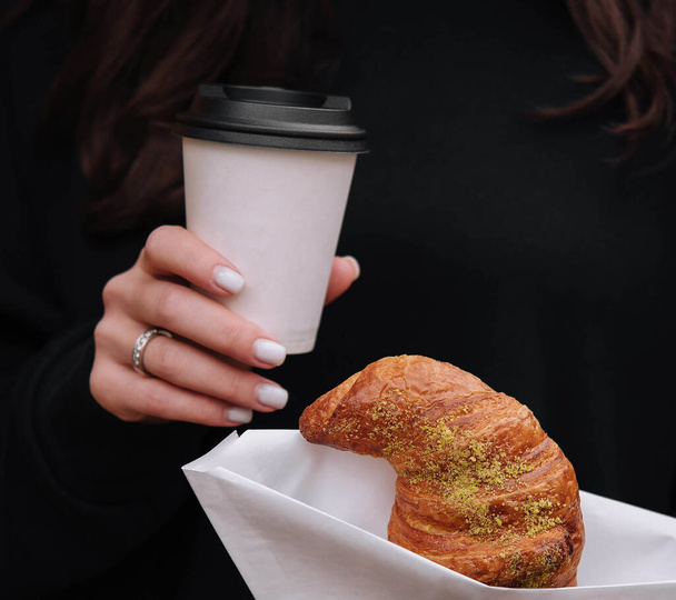 Chica comiendo croissant con pistacho en polvo y beber café en la terraza - Foto, Imagen
