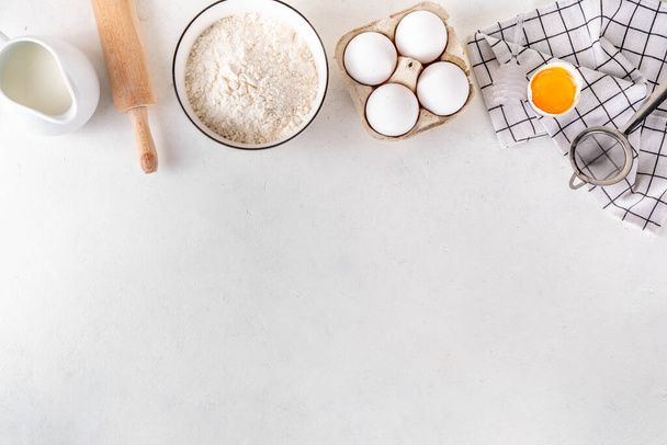 Empty space baking background with bakery ingredients - flour, milk, eggs, rolling pin. Simple pastry baking flat lay top view border - Photo, Image