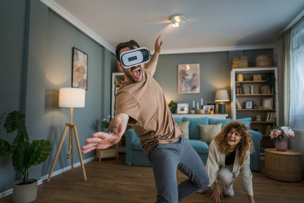 Mann reifen Erwachsenen kaukasischen männlichen Ehemann mit seiner Frau oder Freundin Paar zu Hause genießen Virtual-Reality-VR-Headset mit Brille auf dem Kopf Spaß haben moderne Technologie Freizeitkonzept Kopierraum - Foto, Bild