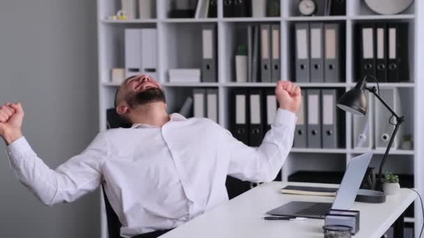 Kafkas erkek ofis çalışanı modern ofiste dizüstü bilgisayarla çalışırken başarılı sonuçları kutluyor. Neşeli zafer, zafer ya da zafer. - Video, Çekim