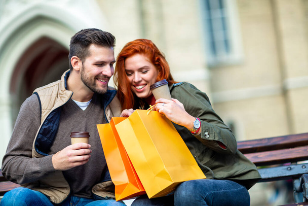 Portret van de gelukkige paar met boodschappentassen na het winkelen in de stad glimlachend en creditcard bedrijf - Foto, afbeelding