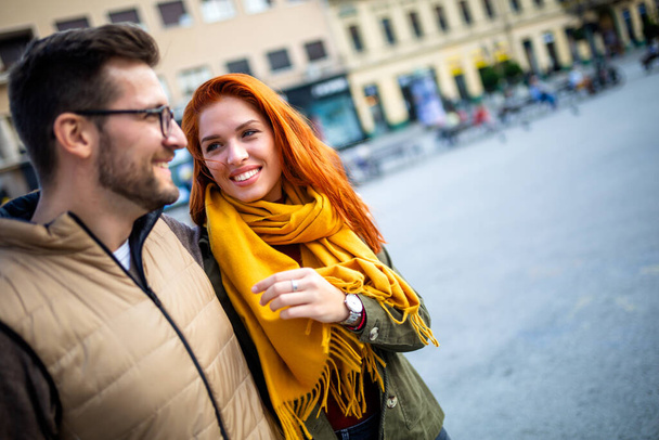 休暇中に楽しむ笑顔のカップル、楽しい散歩や日中の街の通りを探索している若い観光客. - 写真・画像