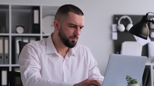 Vermoeide Kaukasische zakenman lijdt aan migraine tijdens het werken met laptop in het kantoor. Hoge werkbelasting, werkspanning, burn-out concept. - Video