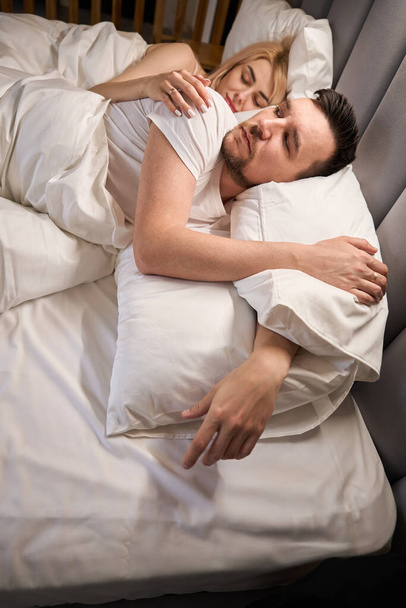 Mladí manželé podřimují na pohodlné posteli, pár je ubytován v líbánkách - Fotografie, Obrázek