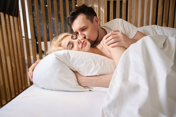 Homme embrasse tendrement sa femme sur la joue, le couple est logé dans la suite nuptiale - Photo, image