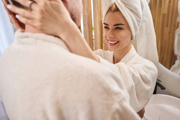 Joyeux jeunes mariés câlins dans la salle de bain, une femme dans un turban serviette - Photo, image
