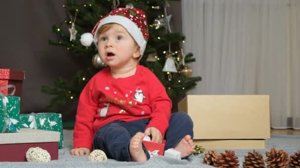 Portret van 11 maanden oude baby in Santa hoed spelen met kerstspeelgoed. - Video