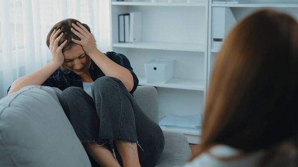 悲しいPTSDの女性は,心理学者,うつ病,または人生の失敗後の悲しみの精神的健康のための治療を受けています. 診療所での感情についての主要な心理学者と話す疲労したトラウマの若い女性 - 写真・画像