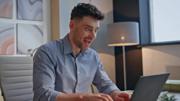 Podekscytowany zwycięzca radujący się w miejscu pracy czytając świetne wiadomości na zbliżeniu laptopa. Wesoły biznesmen czuje się szczęśliwy świętując sukces biznesowy w nowoczesnym biurze. Przepełniony radością przedsiębiorca wyrażający radość - Materiał filmowy, wideo