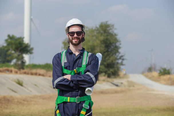 man engineer worker wearing safety uniform holding and reading blueprint working about renewable energy at station energy power wind. technology protect environment reduce global warming problems. - Foto, imagen
