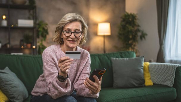 mature woman caucasian female hold credit card online shopping at home - Photo, Image