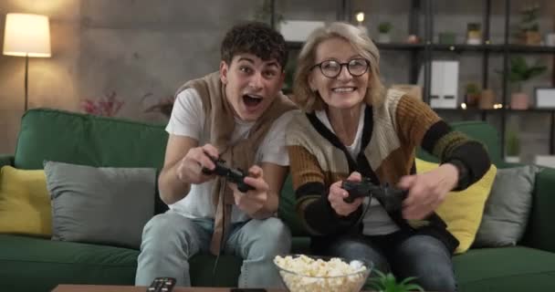 підліток чоловік і його мати зріла жінка чоловік грає в консольну відеогру - Кадри, відео