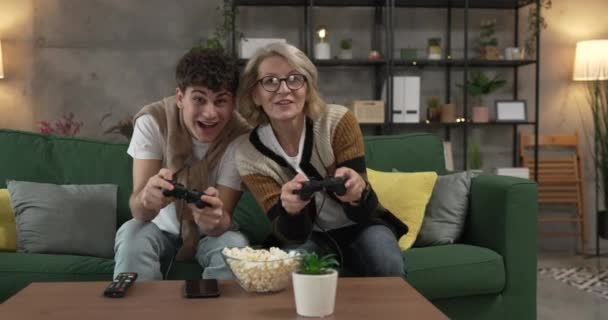 έφηβος άνδρας και η μητέρα του ώριμη γυναίκα άντρας παίζουν κονσόλα βιντεοπαιχνίδι - Πλάνα, βίντεο
