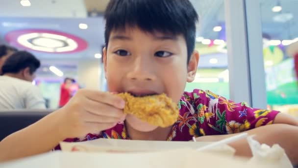 Kleine Aziatische kind geniet van het eten van gebakken kip . - Video