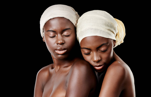 Türban, sarılma ve Afrikalı kadınlar sağlık, sağlık ve saç bakımı için stüdyoya. Salon estetiği, kültür ve insanlar siyah arka planda aksesuarlar, kozmetik ürünler ve başörtüsüyle kucaklaşıyor.. - Fotoğraf, Görsel