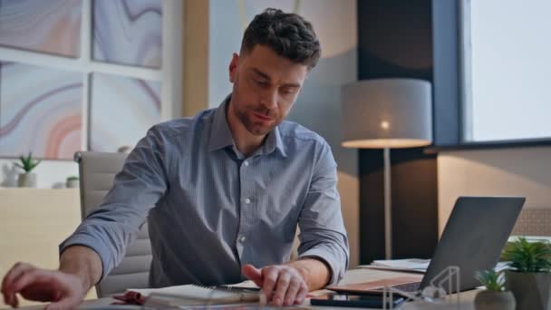Embarrassed businessman searching documents at messy workplace closeup. Worried sad employee writing notes looking laptop screen at office. Stressed specialist feeling nervous about work problems - Footage, Video