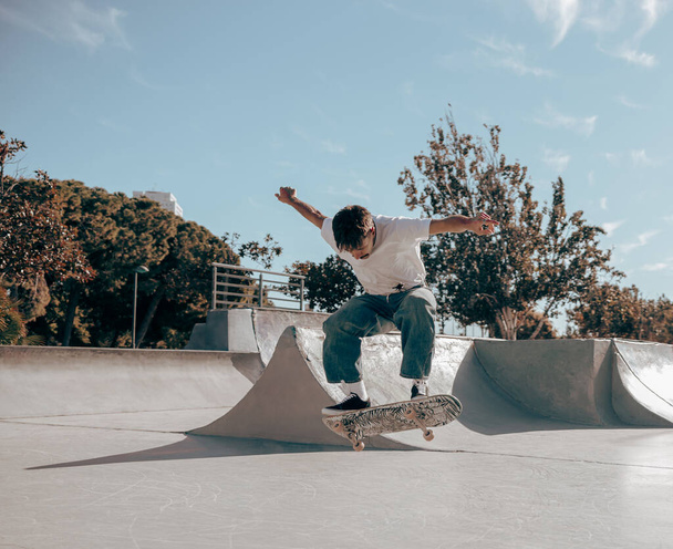 Młody człowiek robi sztuczki na deskorolce w skateparku. Koncepcja aktywnego sportu - Zdjęcie, obraz