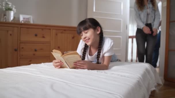 Glückliche moderne Familien wecken ihr kleines Mädchen am Wochenende mit spielerischem Kitzeln, indem sie ihre Liebe und Zuneigung zu ihrer kleinen Tochter zum Ausdruck bringen, gemeinsam lachen und lächeln. Anspruchsvoll - Filmmaterial, Video