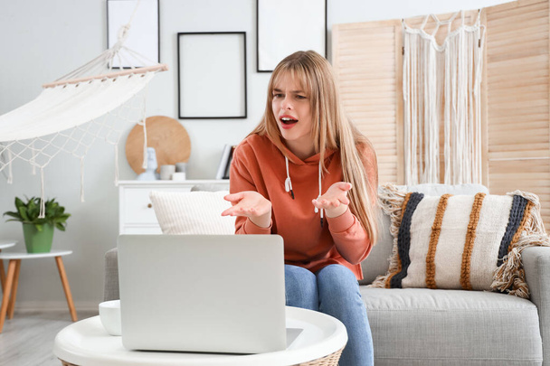 Dizüstü bilgisayarlı mutsuz genç kız evde görüntülü sohbet ediyor. - Fotoğraf, Görsel