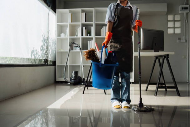 Жінка-домогосподарка посміхається і носить рукавичку, готується до прибирання офісу. - Фото, зображення