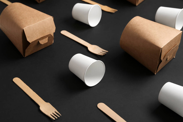 Бумажные чашки, коробки и вилки на черном фоне - Фото, изображение