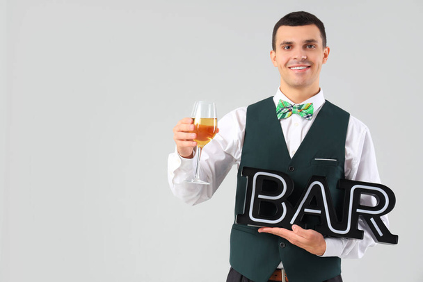 Young barman with wine on grey background - Photo, Image