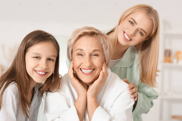 Маленькая девочка с мамой и бабушкой, улыбающимися в ванной, крупным планом - Фото, изображение