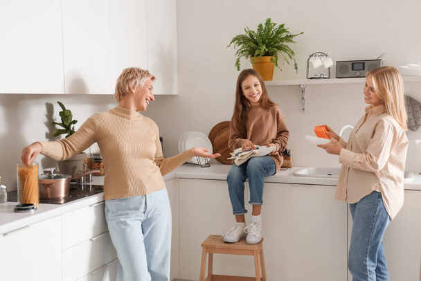Menina com sua mãe e avó lavar pratos na cozinha - Foto, Imagem
