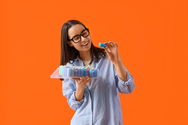 Schneiderin in Brille mit Fadenspulen auf orangefarbenem Hintergrund - Foto, Bild