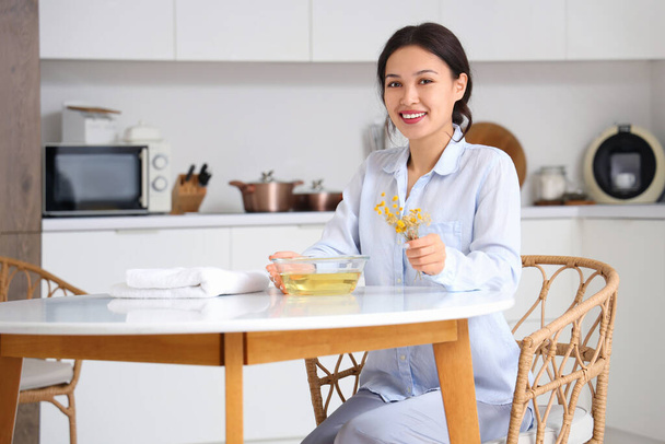 Fiatal ázsiai nő készül gőz inhaláció gyógynövények asztalnál a konyhában - Fotó, kép