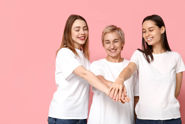 Vrouwen die elkaars handen op een roze achtergrond leggen. Vrouwengeschiedenis maand - Foto, afbeelding