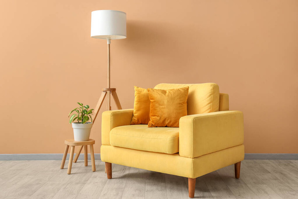 Interiér obývacího pokoje s křeslem, polštáři a lampou u béžové stěny - Fotografie, Obrázek