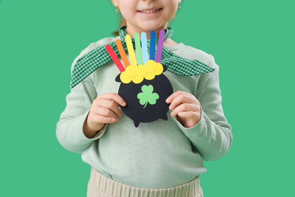 Nettes kleines Mädchen mit Papiertopf mit Münzen und Regenbogen auf grünem Hintergrund. St. Patrick 's Day Feier - Foto, Bild