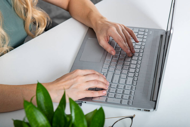 Nahaufnahme einer professionellen Frauenhand, die fleißig auf einem Laptop tippt, während sie konzentriert und zielstrebig arbeitet und ihre Produktivität demonstriert. - Foto, Bild