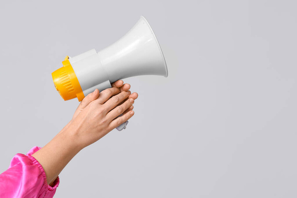 Female hands with megaphone on grey background - Photo, Image