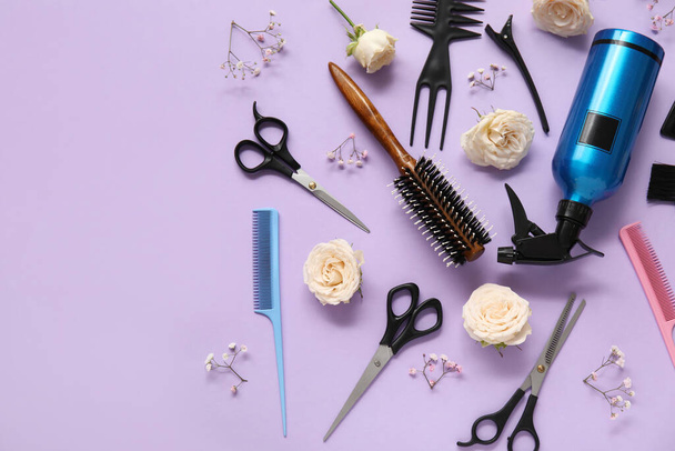 Hairdresser's tools with beautiful roses and gypsophila flowers on lilac background - Photo, Image
