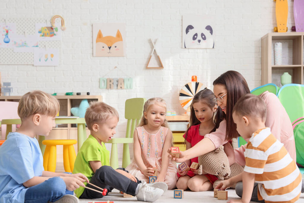 Crianças pequenas e educador brincando com cubos no jardim de infância - Foto, Imagem