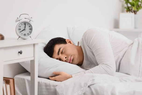 Молодой человек с будильником спит в спальне, крупным планом - Фото, изображение