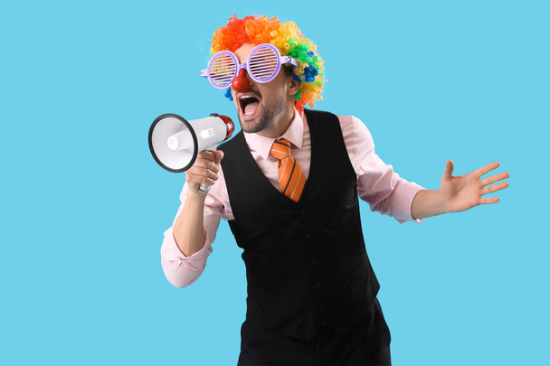 Young businessman in funny disguise with megaphone screaming on blue background - Photo, Image