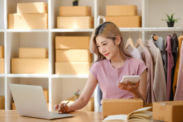 Online vásárlási koncepció, Női vállalkozó kiszámítja a megrendelést, és azt írja címet csomagküldő dobozok. Kiváló minőségű fénykép - Fotó, kép