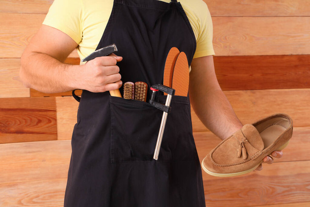 Male shoemaker with tools and shoe on wooden background, closeup - Fotó, kép