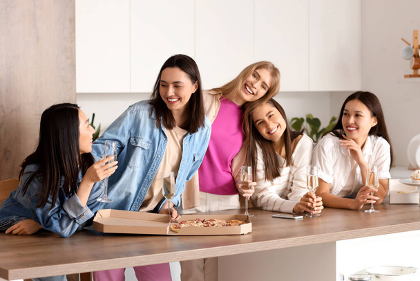 Mujeres jóvenes con champán y sabrosa pizza en la despedida de soltera en la cocina - Foto, imagen