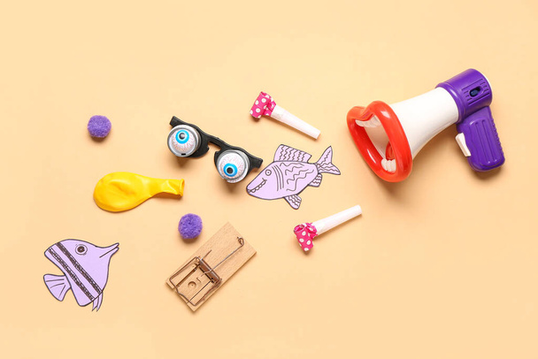 Megáfono con gafas divertidas, ratonera y peces de papel sobre fondo beige. Día de los Inocentes - Foto, Imagen