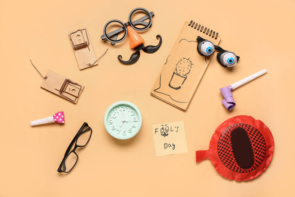 Gafas graciosas con despertador, cojín whoopee y ratoneras sobre fondo beige. Día de los Inocentes - Foto, imagen