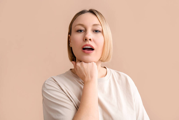 Woman doing face building exercise on beige background - Foto, imagen