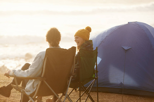 Счастливы, кемпинг и пара в палатке в отпуск, приключение или отдых на природе для путешествия. Smile, любовь и молодые мужчина и женщина разговаривают, связывая и расслабляя на открытом воздухе для поездки в выходные на seaside - Фото, изображение