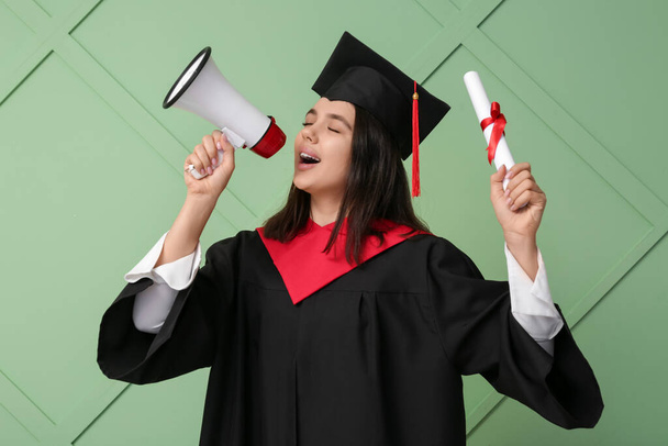 Γυναίκα απόφοιτος φοιτητής με δίπλωμα και μεγάφωνο σε πράσινο ξύλινο φόντο - Φωτογραφία, εικόνα