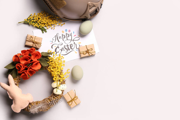 Composición con tarjeta de felicitación, hermosa decoración de Pascua y casco militar sobre fondo claro - Foto, Imagen