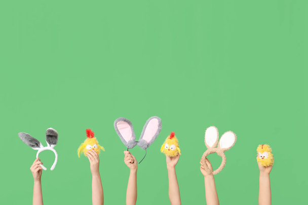 Vrouwelijke handen met paashaas oren hoofdbanden met speelgoed kippen op groene achtergrond - Foto, afbeelding