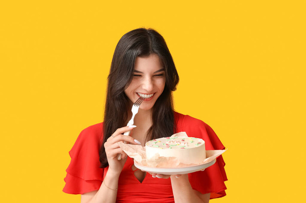 Gyönyörű fiatal nő édes bento torta és villa sárga háttérrel. Nemzetközi nőnap - Fotó, kép